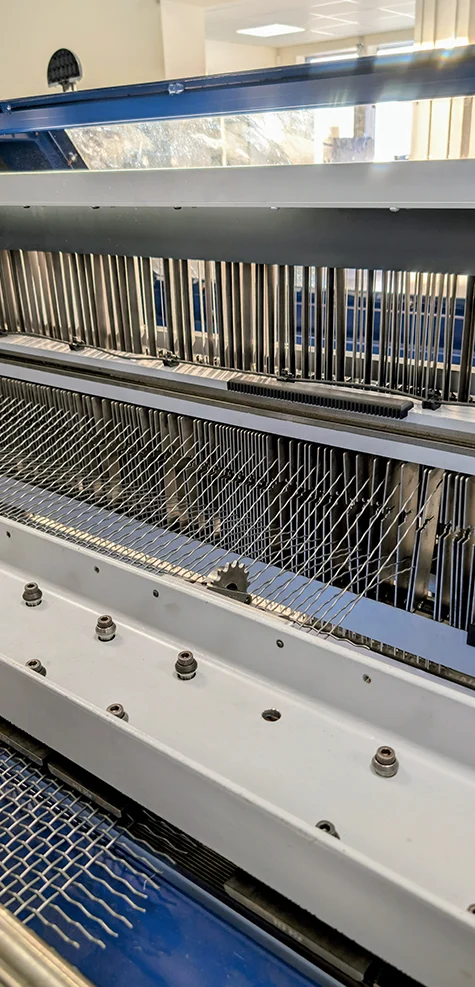 Maskinens inre delar med många långa metalldelar och nät.